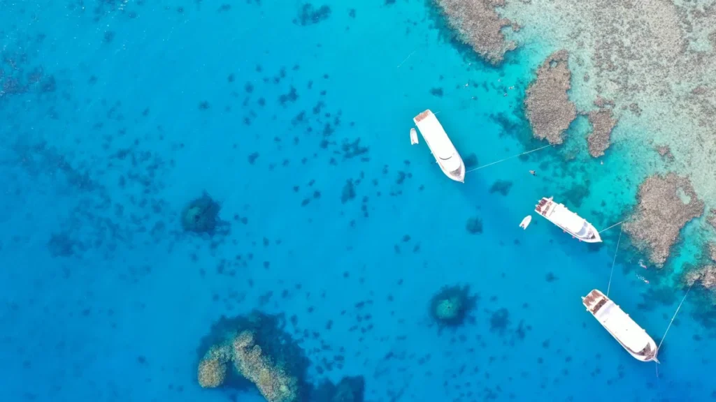 Boten liggen voor anker boven koraalriffen in het heldere blauwe water van de Rode Zee bij Hurghada