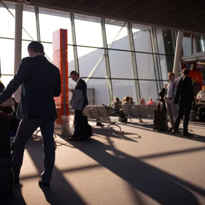 Reizigers met handbagage in een zonnige vertrekhal op de luchthaven, wachtend op hun vlucht